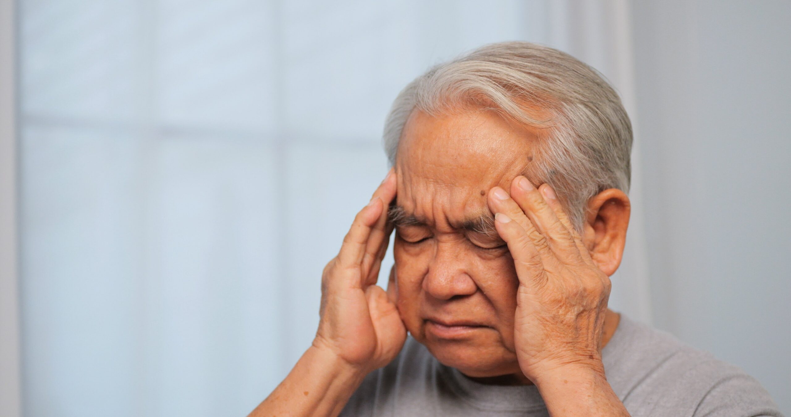 Elderly man holding his head in pain.